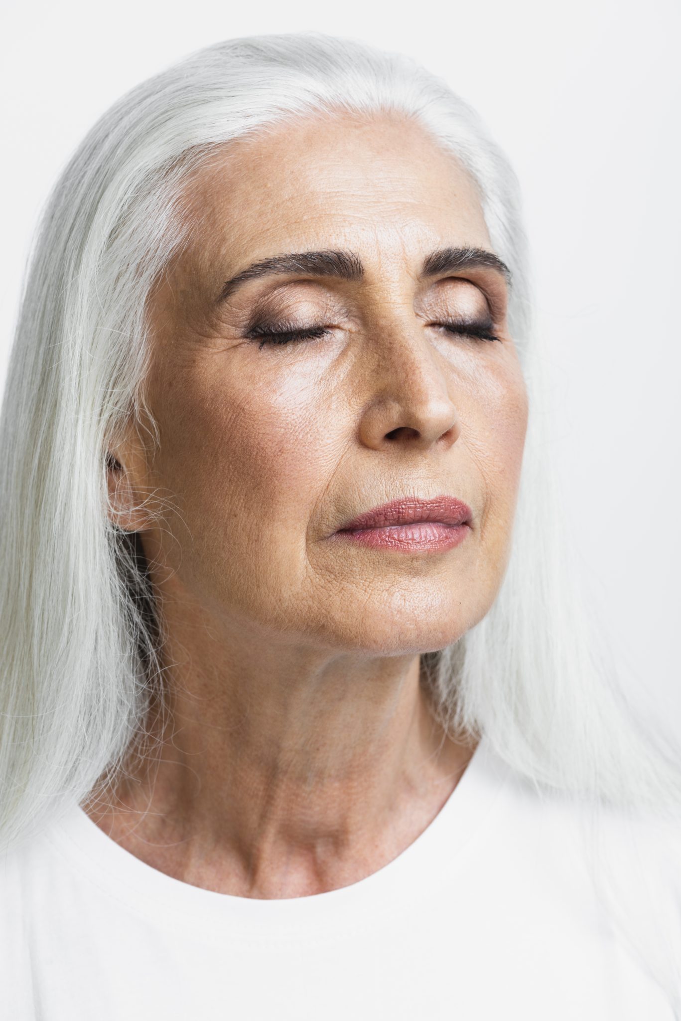 Close-up of a senior woman with long white hair and eyes closed, highlighting natural skin texture, often used to represent spider vein or skin rejuvenation treatments at PUR Skin Clinic.
