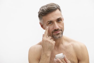 Middle-aged man applying under-eye cream as part of advanced skincare for men at PUR Skin Clinic