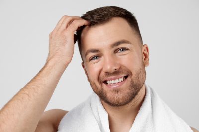 Smiling man with full, healthy hair after hair restoration treatment at PUR Skin Clinic